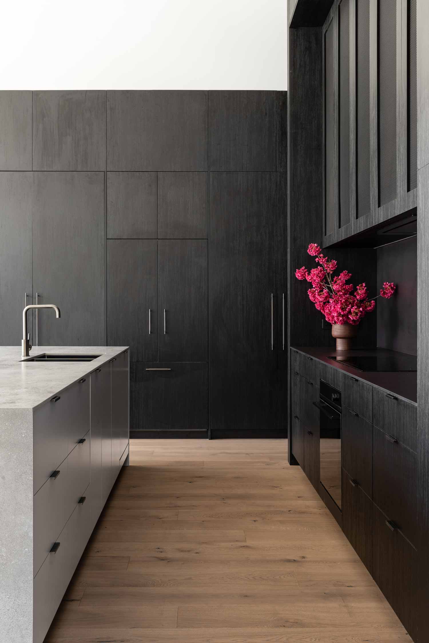 Modern-industrial-interior-design-in-a-contemporary-dark-kitchen-with-black-cabintery-and-gun-metal-taps-pop-of-pink