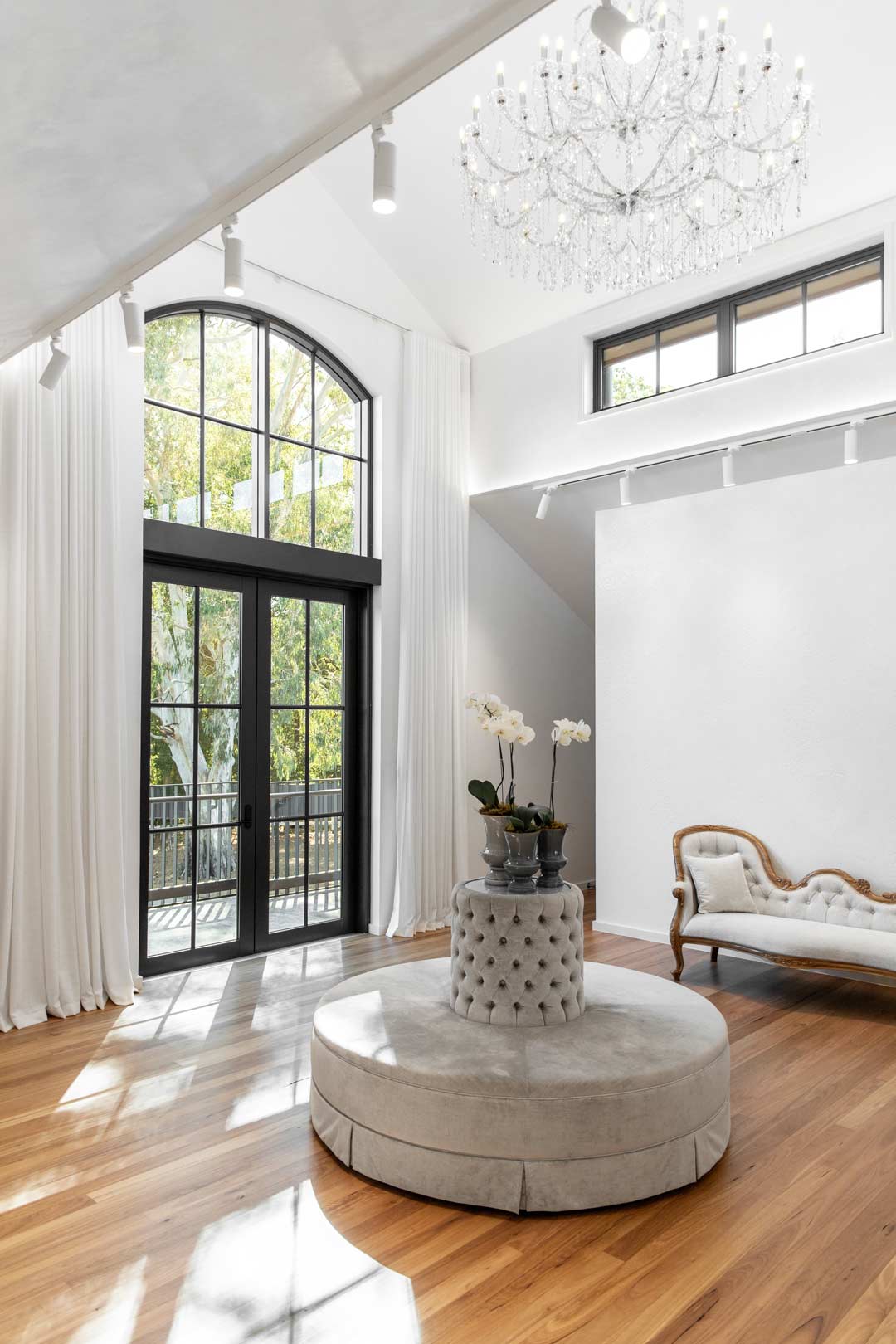 A-high-celing-dressing-room-in-an-old-money-style-home-has-velvet-ottoman-and-a-gilded-gold-lounge