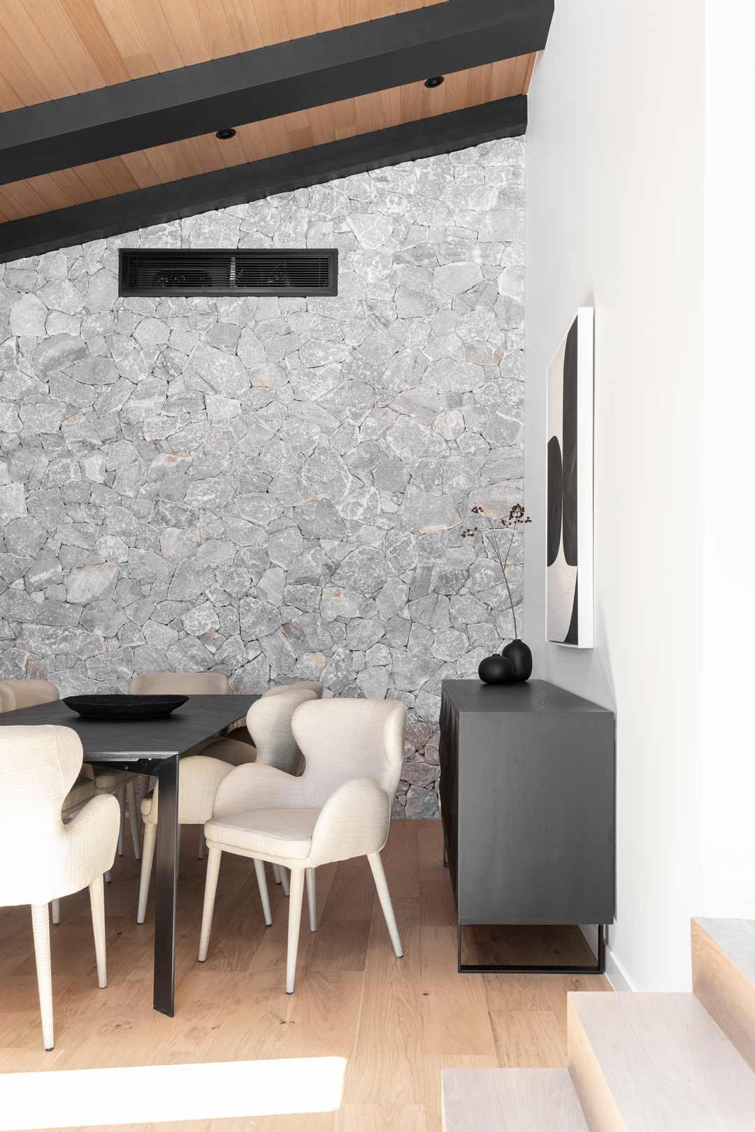 A-monochomatic-dining-room-with-a-stone-feature-wall-and-timber-ceiling-in-an-alpine-lodge-style-home