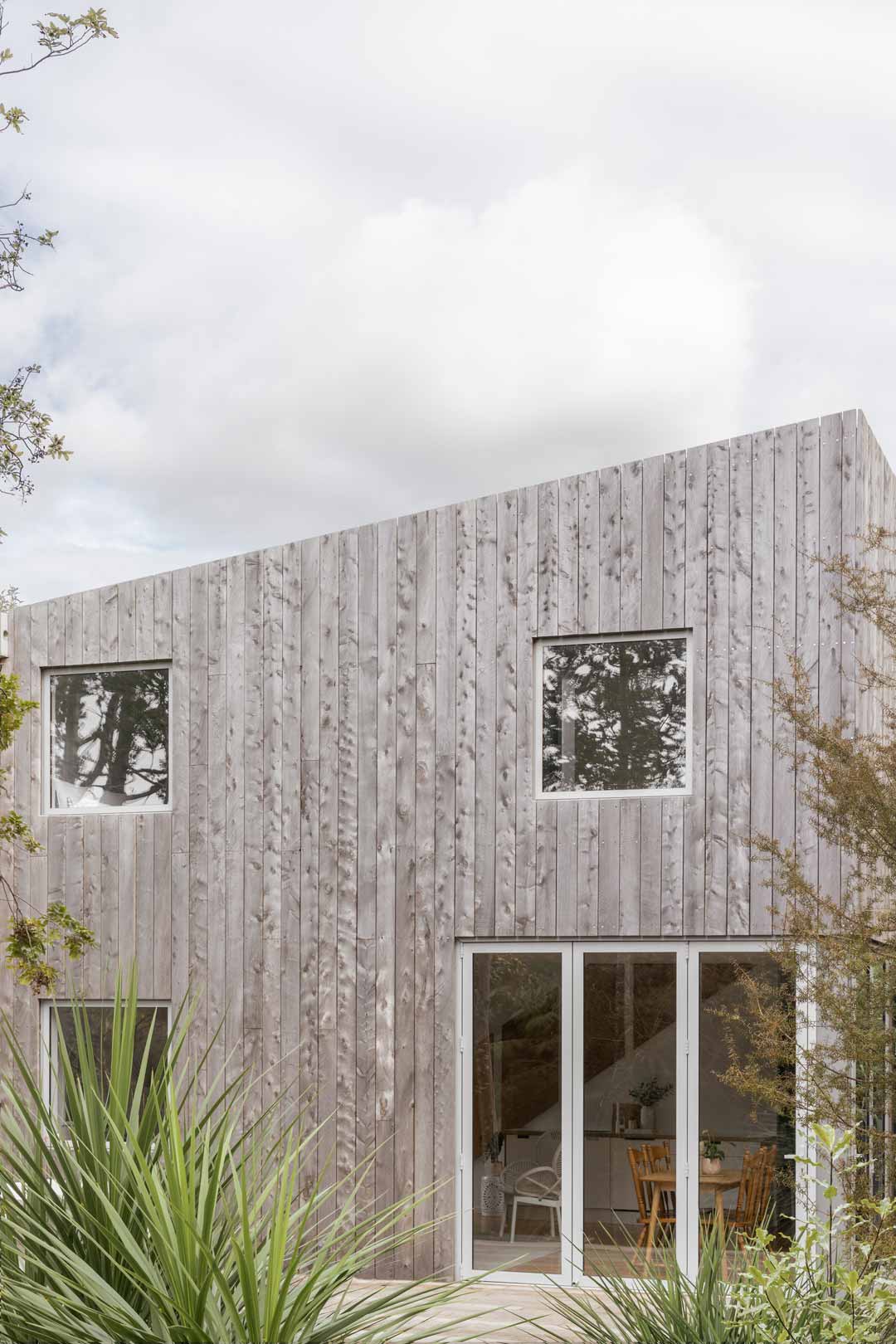 A-tiny-home-in-New-Zealand-blends-into-the-coastal-landscape-with-a-neutral-palette-and-timber-vertical-panels