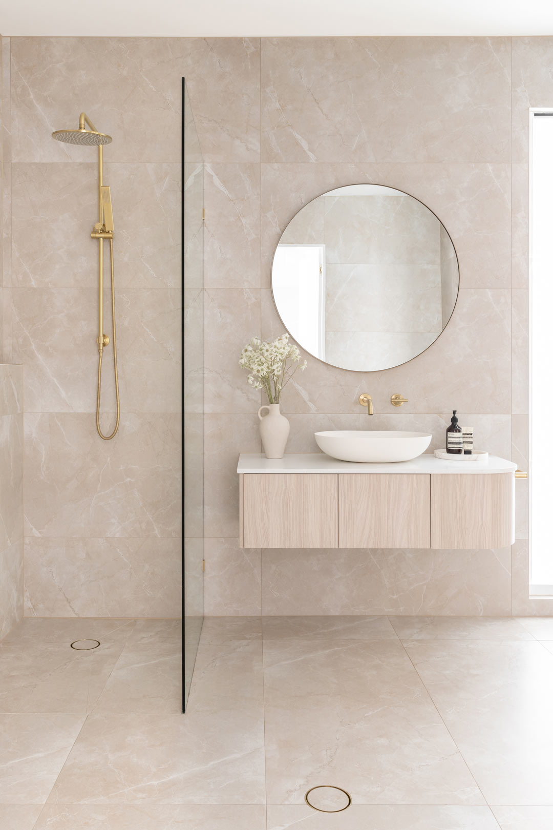 A-neutral-bathroom-interior-design-in-a-renovated-queenslander-featuring-brushed-brass-tapware-a-light-timber-vanity-and-a-soft-colour-palette