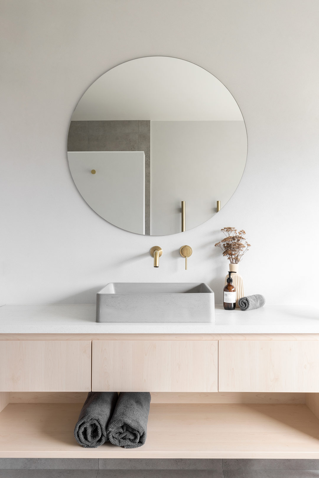 A-simple-bathroom-with-a-neutral-colour-palette-concrete-basin-and-brushed-brass-tapware
