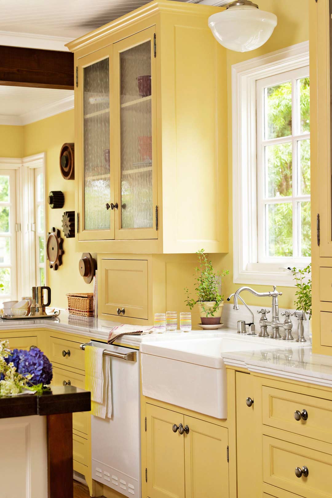 A-bright-warm-yellow-country-style-kitchen-with-yellow-cabinetry-and-a-farmhouse-sink