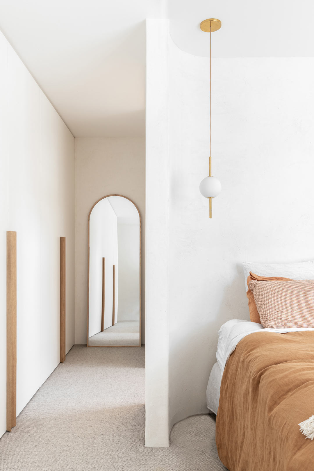 Simple-mediterranean-interior-design-in-this-crisp-clean-bedroom-with-muted-bed-linen-and-an-arched-mirror