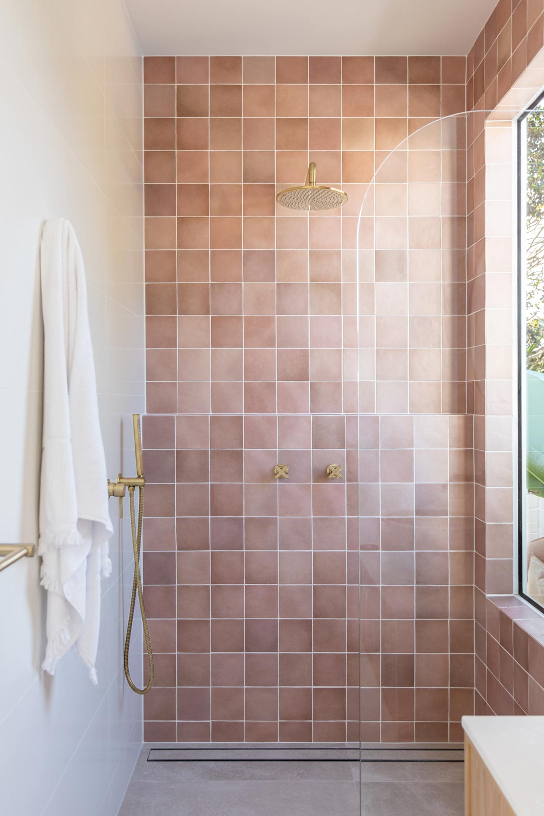 A-shower-feature-wall-with-handmade-muted-pink-tiles-and-brushed-brass-tapware
