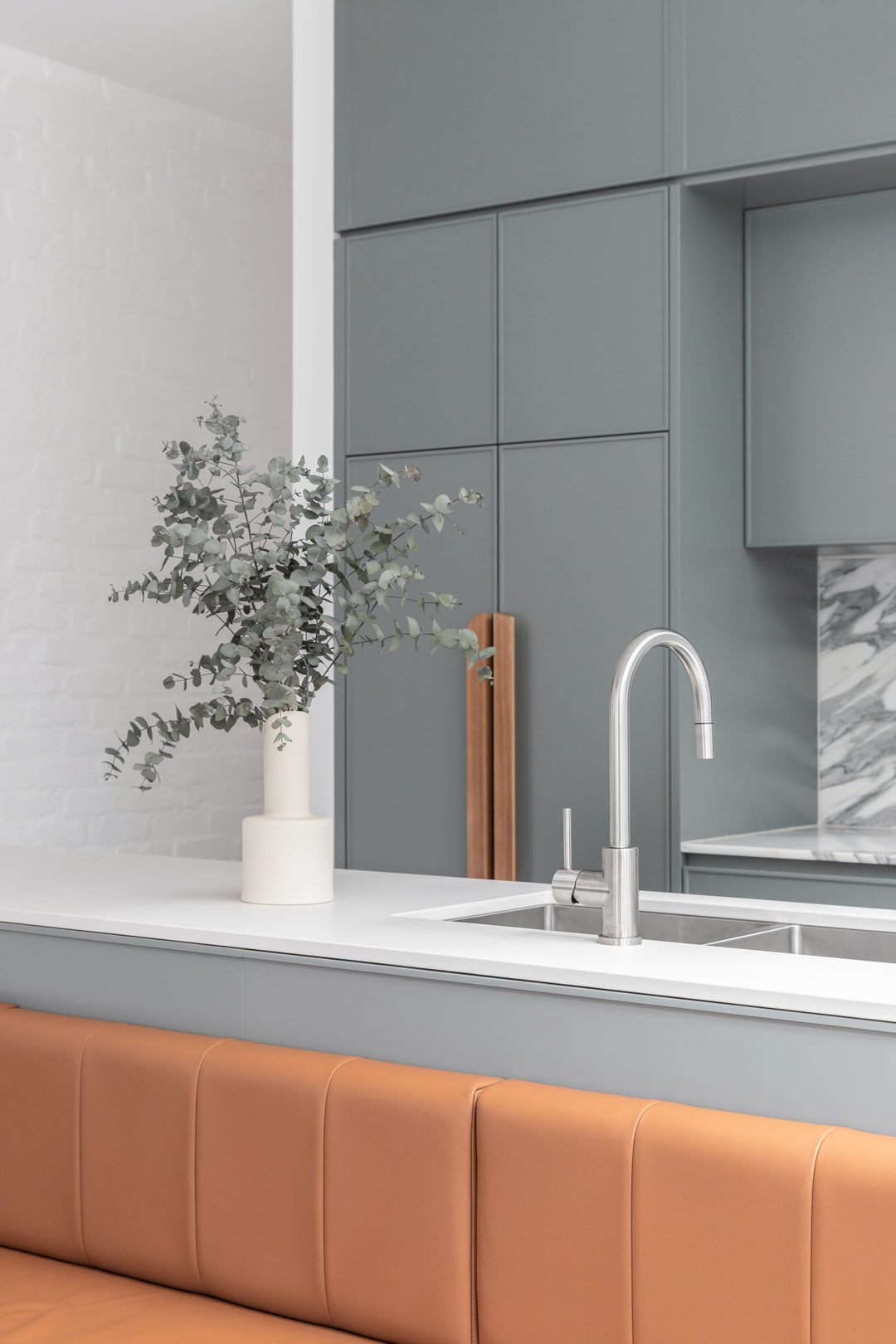 Modern-coastal-kitchen-and-dinind-space-with-a-built-in-dining-bench-soft-warm-leather-blue-cabinetry-stainless-steel-tapware-and-marble-splash-back-1
