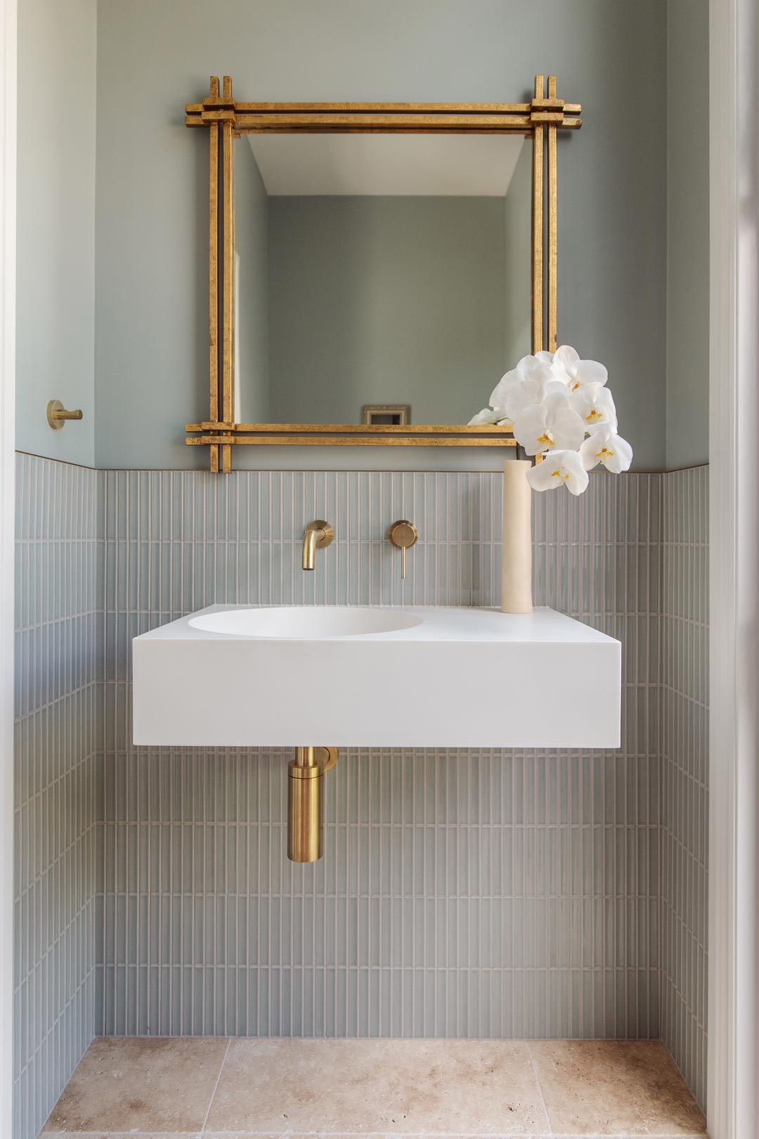 Soft-green-walls-and-finger-tiles-in-this-art-deco-bathroom-with-a-gold-mirror-and-brushed-brass-tapware