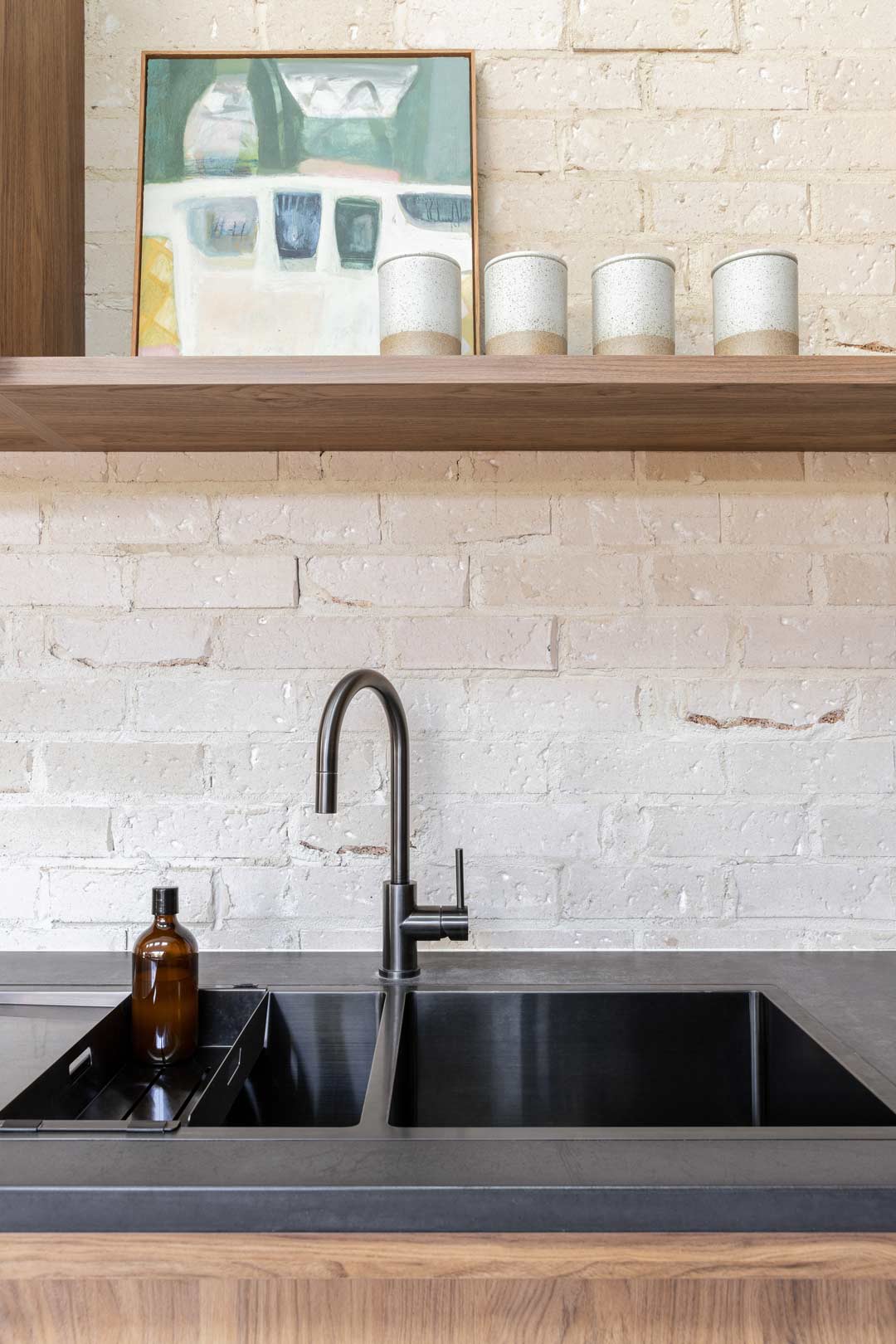Brushed-gunmetal-kitchen-tap-paired-with-a-brushed-gunmetal-matching-double-sink-and-open-shelving