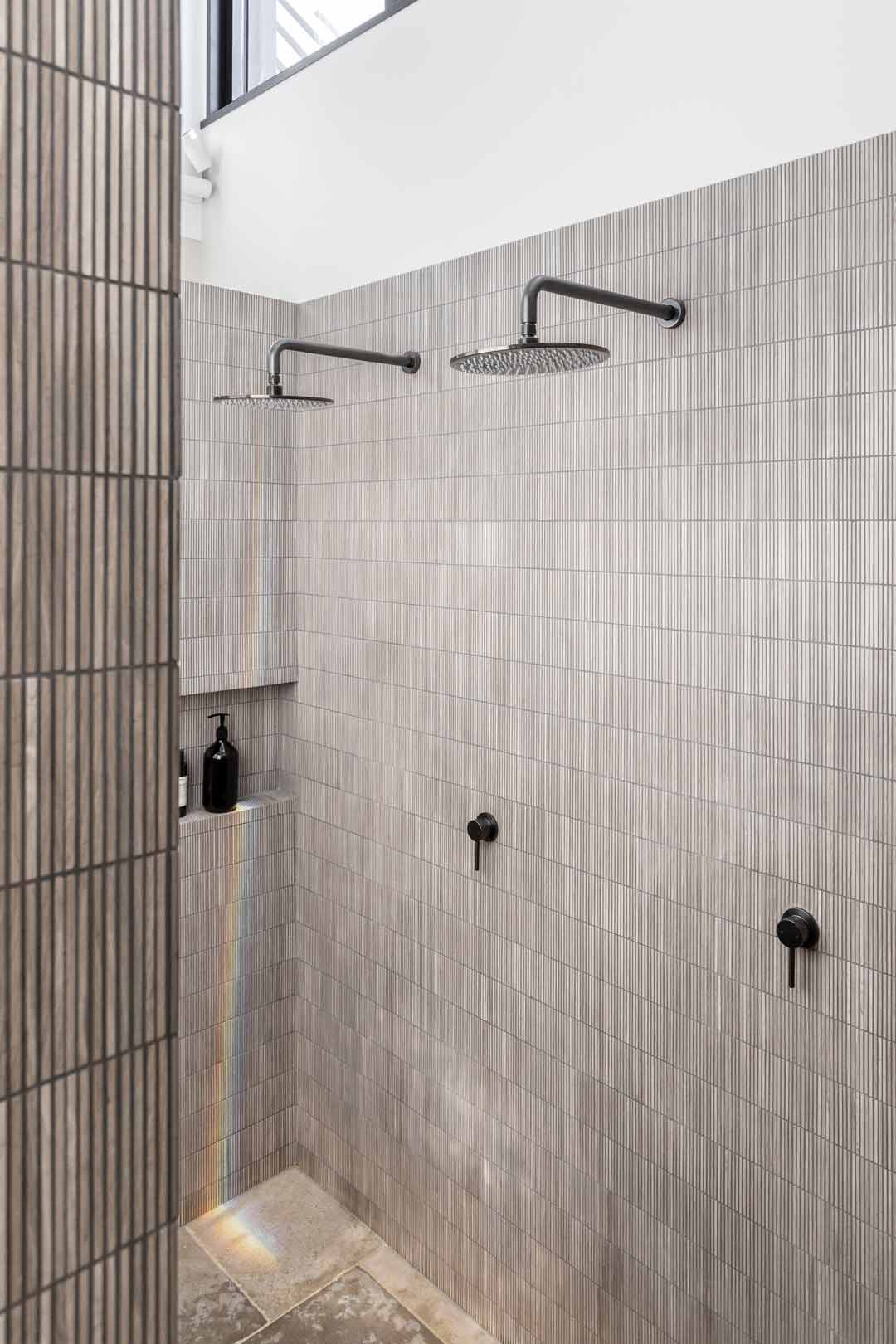 Travertine-slither-feature-tiles-paired-with-brushed-gunmetal-shower-fittings-and-a-skylight