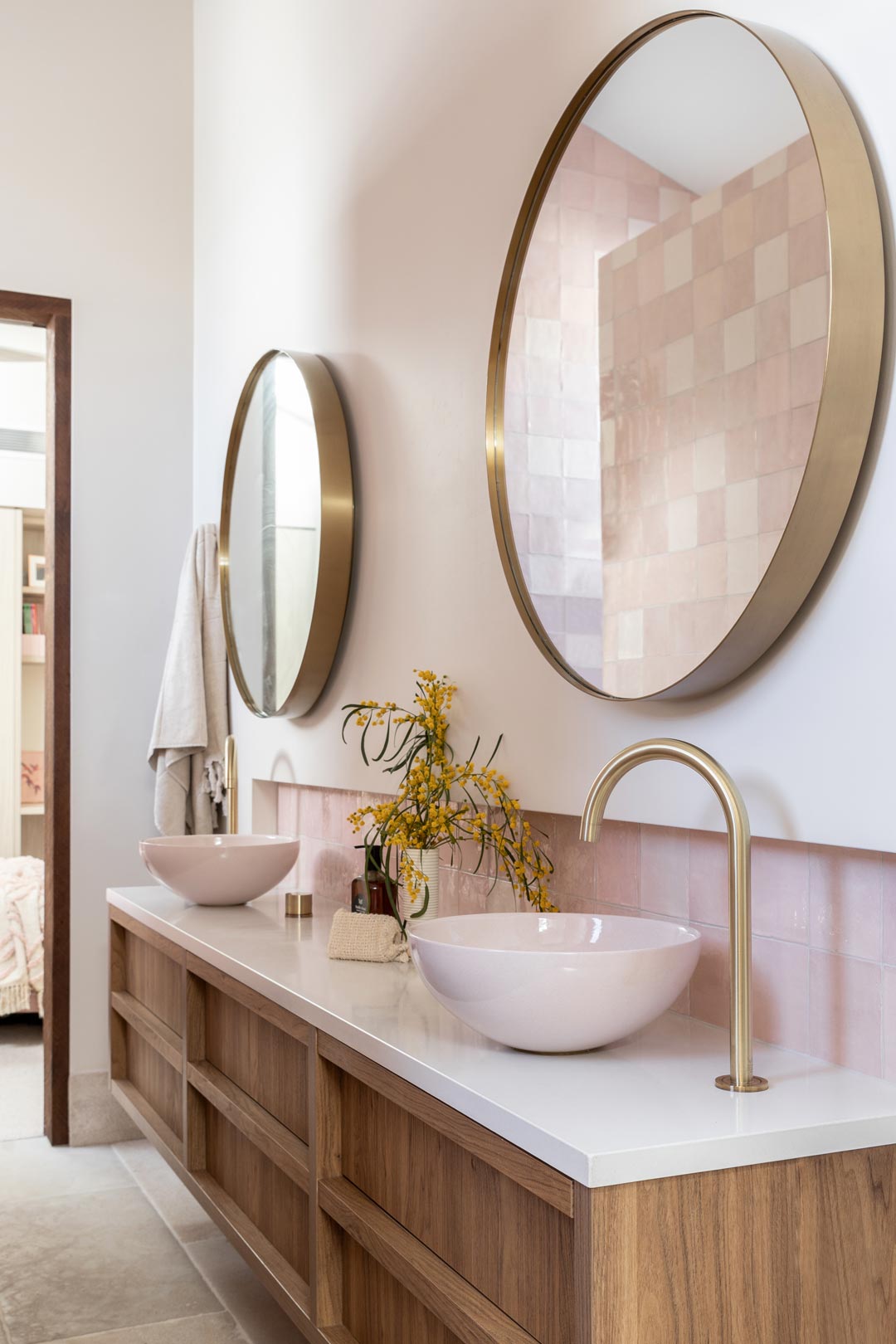 Pink-feature-tiles-with-brushed-brass-tapware-and-brushed-brass-round-mirrors