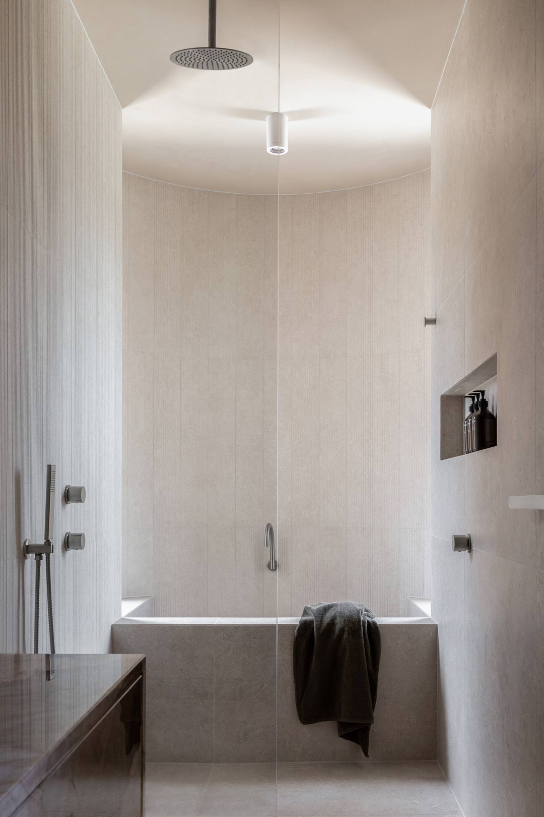 A-spa-like-bathroom-with-a-ceiling-shower-dropper-and-a-built-in-concrete-bath