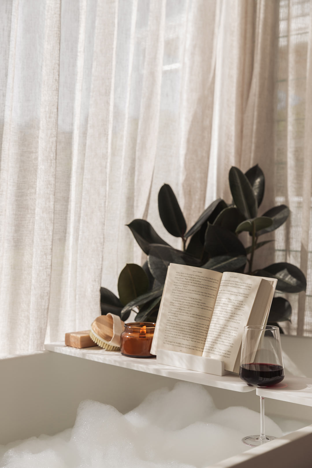 Practice-relaxation-and-self-care-with-a-bubble-bath-candle-book-and-glass-of-wine